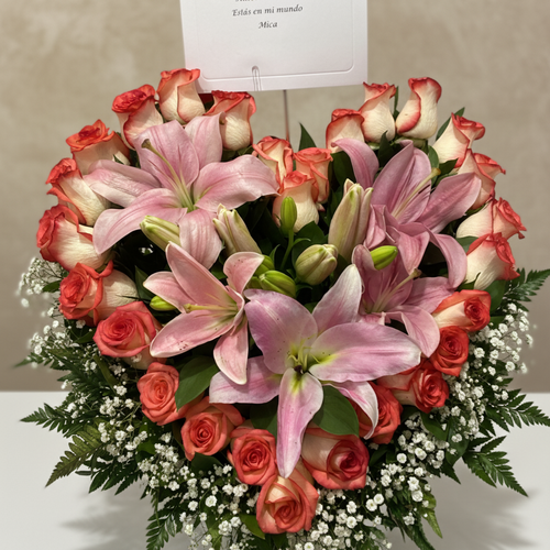 Arreglo floral en forma de corazón con lirios y rosas Arreglo floral en forma de corazón con lirios rosados y rosas rojas y blancas, decorado con gypsophila y follaje verde, con tarjeta en la parte superior
