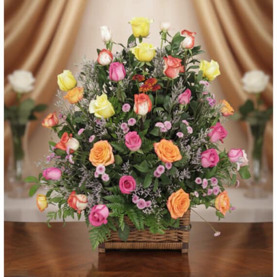 Arreglo DONNIA: Cesta Elegante con 34 Rosas para Sorprender Arreglo floral DONNIA en cesta de mimbre con 34 rosas de colores variados (rosas, amarillas, naranjas) y follaje verde, sobre
