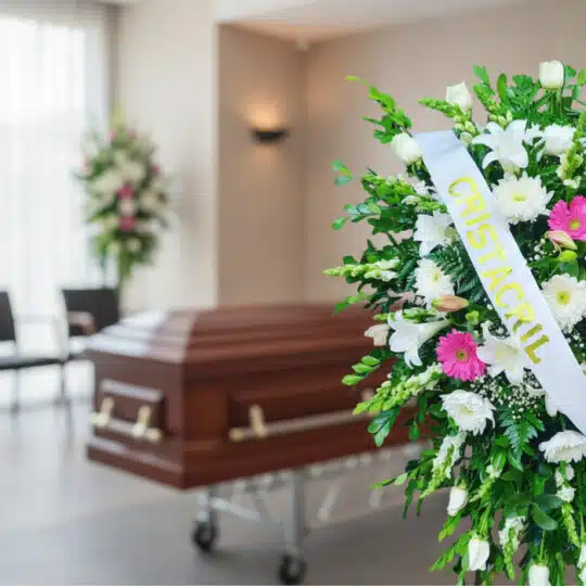 Pedestal fúnebre Sagrado con flores blancas y fucsias, cinta personalizada, en primer plano de una sala de velación moderna c
